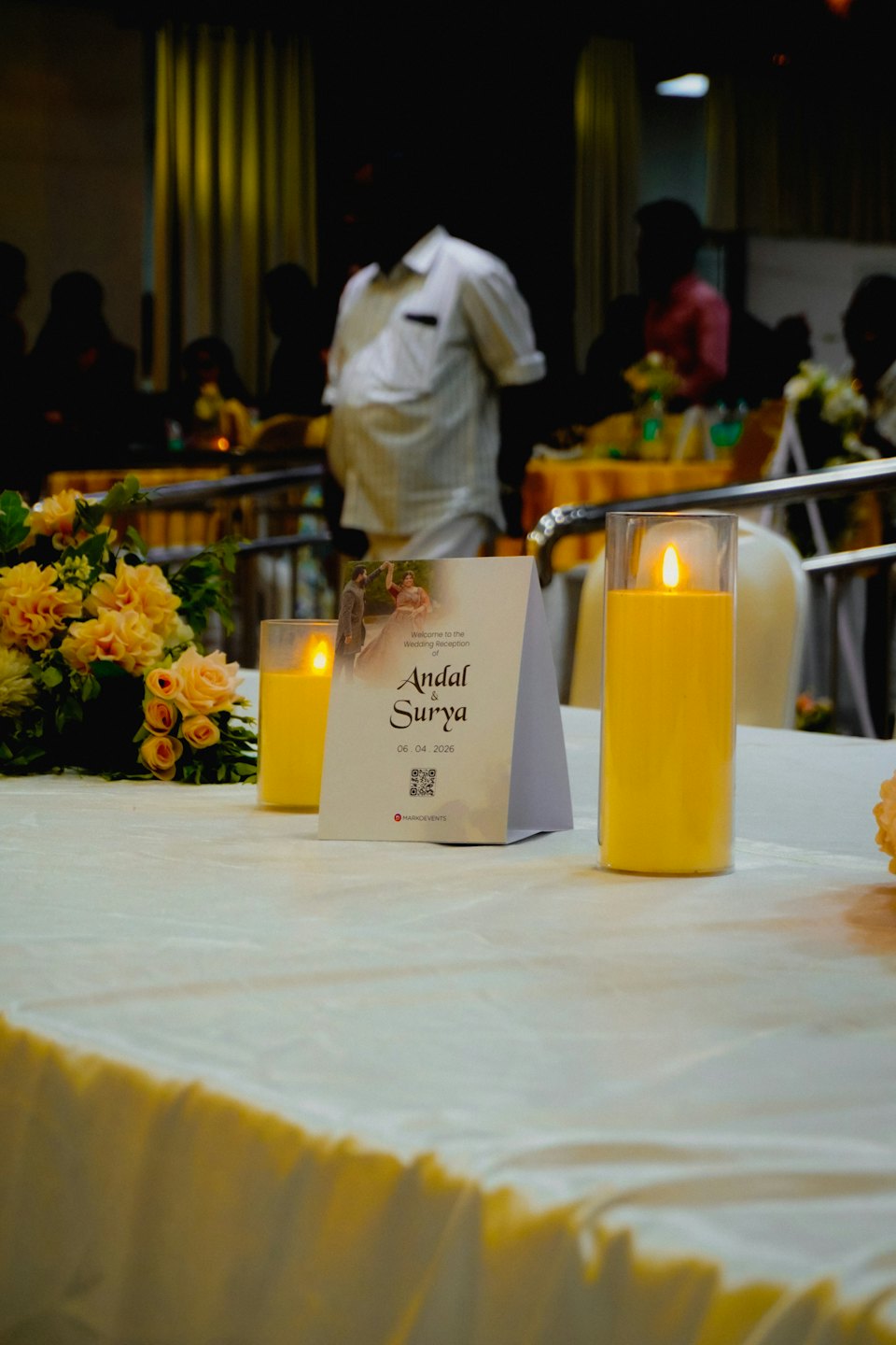 Un bouquet floreale e candele accese decorano un tavolo per ricevimenti nuziali.