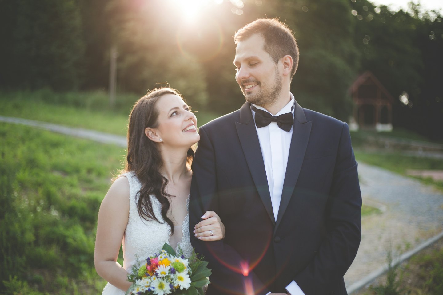 Una sposa e uno sposo si abbracciano in un parco verde.
